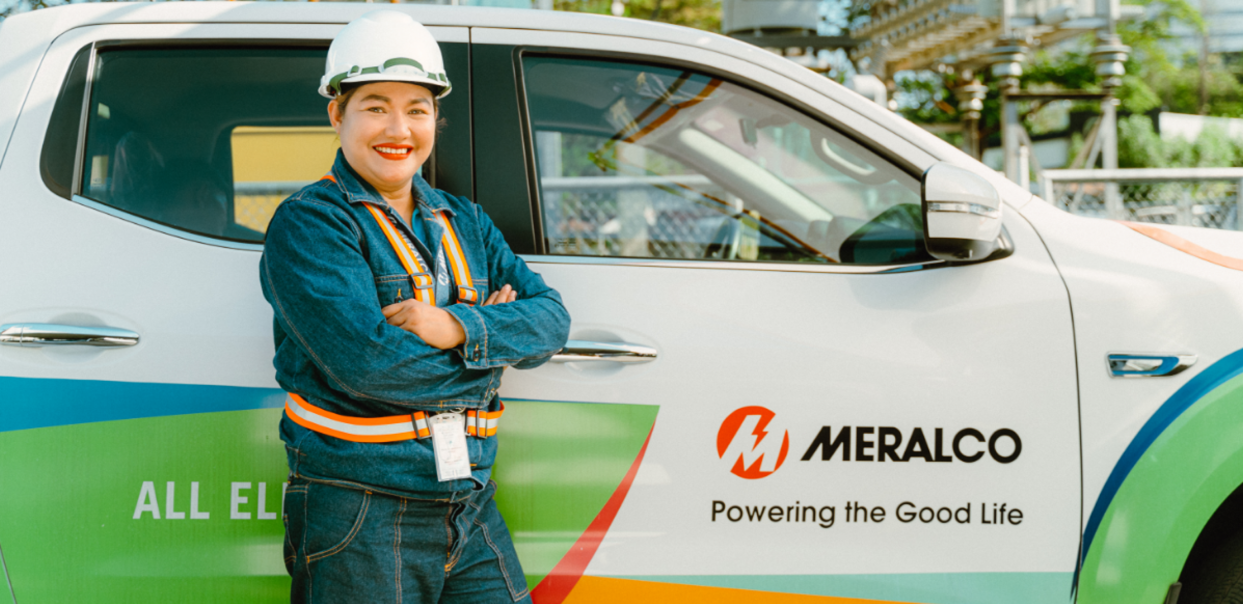 Meralco employee beside an all-electric company vehicle